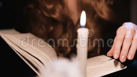 特写迷人的白种人女孩翻阅一本书蜡烛在燃烧万圣节庆祝概念浅视频的预览图