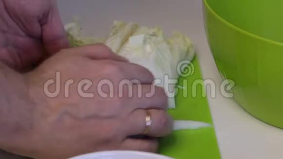 一个人做一份北京卷心菜沙拉用刀子把卷心菜切成切割板然后扔进容器里在旁边视频的预览图