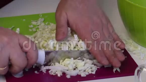 一个人做一份北京卷心菜沙拉用一把刀在切割板上磨碎卷心菜然后把它扔进容器里视频的预览图