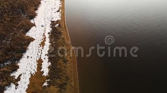 在温暖的冬日鸟瞰海岸线岸边的黄草和积雪全球变暖视频的预览图