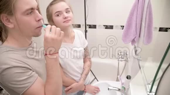 年轻夫妇在浴缸里男人刷牙女孩在等待微笑特写视频的预览图