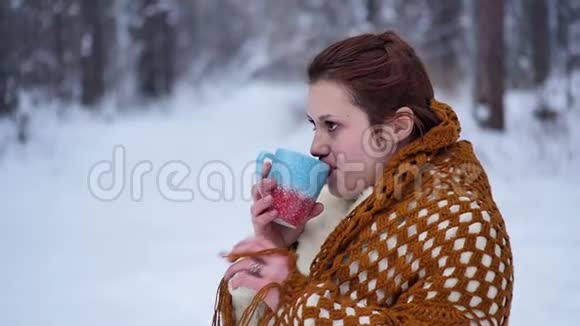 一个女人正在雪地森林里喝热茶或咖啡一个漂亮的女孩想在冬天取暖视频的预览图