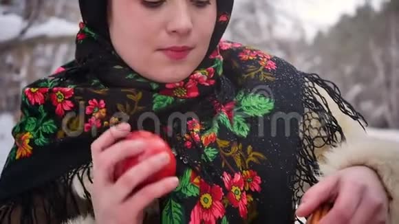 穿着俄罗斯传统服装的年轻女子在冬天的森林里手里拿着一篮子苹果慢动作视频的预览图