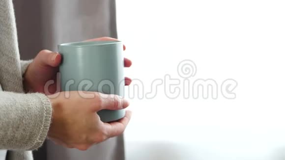 女人喝热茶或咖啡用热气腾腾的杯子把手举起来视频的预览图