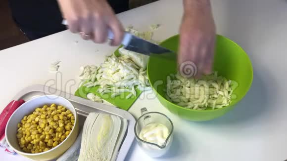 一个人做一份北京卷心菜沙拉用刀子把卷心菜切成切割板然后扔进容器里在旁边视频的预览图