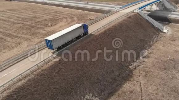 一辆大型卡车和一辆拖车沿着土路行驶在附近寻找掉头的地方视频的预览图