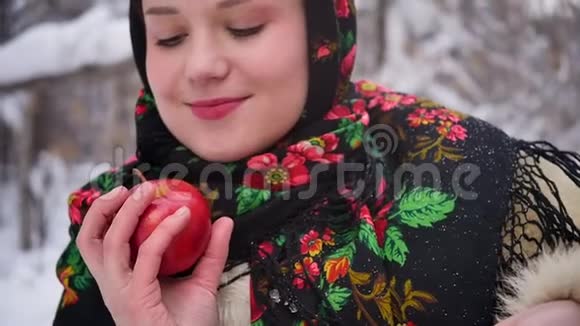 穿着俄罗斯传统服装的年轻女子在冬天的森林里手里拿着一篮子苹果慢动作视频的预览图