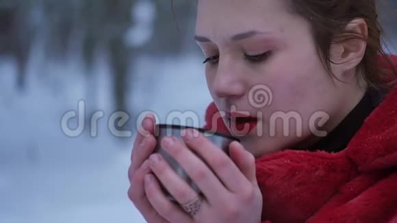 一个女人正在雪地森林里喝热茶或咖啡一个漂亮的女孩想在冬天取暖视频的预览图