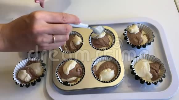 一个女人把有可可的面团放在松饼烤盘里做一个大理石蛋糕特写视频的预览图