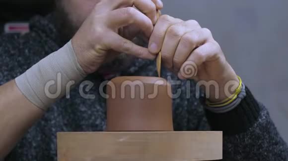 工匠用特殊的木刀从茶壶中取出多余的粘土手工泥茶壶宜兴为茶道紫色紫色视频的预览图