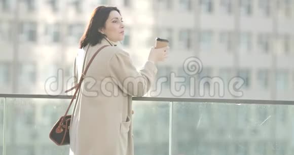 从侧面可以看到年轻的白种人穿着优雅的外套在城市户外喝咖啡成功自信视频的预览图
