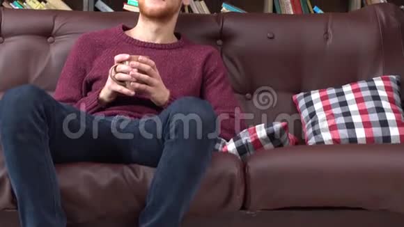 红发男子坐在图书馆喝热茶放松视频的预览图