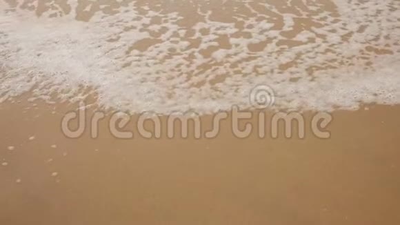 泡沫的海浪覆盖着沙质的海岸视频的预览图