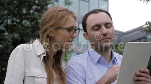 微笑的男人和女人在户外使用平板电脑视频的预览图