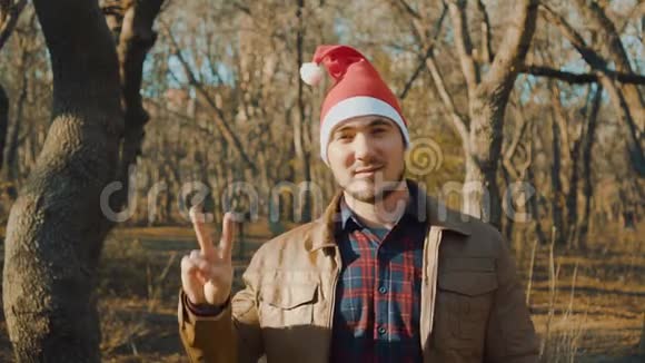 年轻的圣诞老人穿着皮夹克微笑用两根手指表示胜利的象征视频的预览图