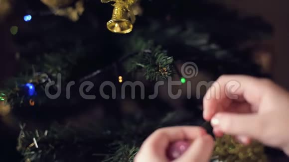 一个小女孩的手的特写装饰了一棵新年树把玩具挂在树枝上视频的预览图