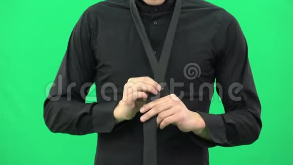 穿黑色衬衫的人正在绿色屏幕上系着一条黑色领带视频的预览图