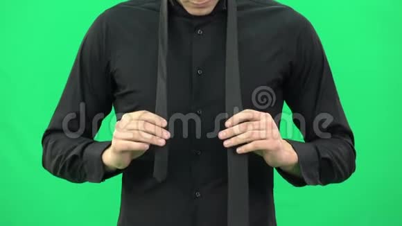穿黑色衬衫的人正在绿色屏幕上系着一条黑色领带视频的预览图