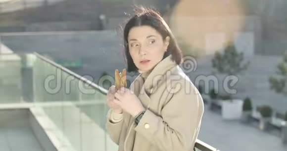布鲁内特高加索女人站在城市街道上饿着肚子吃三明治丰满女商人的肖像视频的预览图
