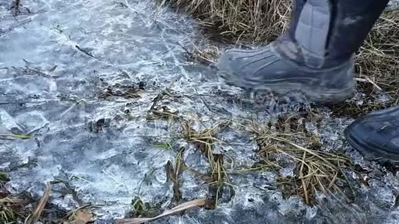 特写镜头人的双脚穿着高靴踩在冰上掉进水坑里视频的预览图