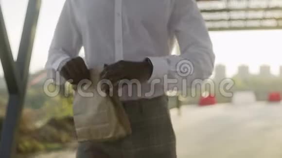 穿白色衬衫的年轻非裔美国商人从包裹里拿出一个羊角面包视频的预览图