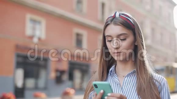 穿着条纹衬衫的年轻漂亮女孩在智能手机上拨打电话和打电话交谈和微笑视频的预览图