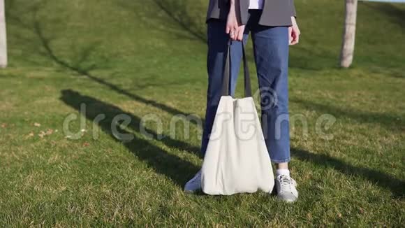 棉花袋在女人手映衬着公园里绿草如茵的背景回收和再利用的概念视频的预览图