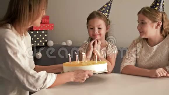微笑的母亲和女儿在家里的生日蛋糕上吹蜡烛家庭和庆祝的概念视频的预览图
