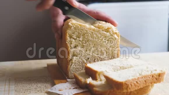 全麦面包放在厨房的木盘上厨师拿着刀切割切新鲜的硬面包特写这就是视频的预览图