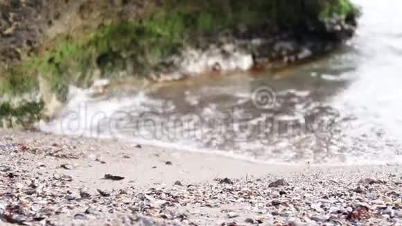 海浪拍打着海岸长满绿苔的大姜石视频的预览图