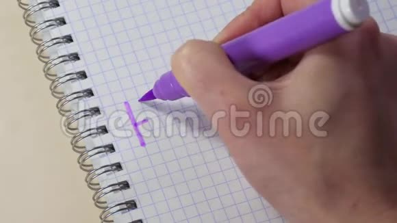 一个女人手在记事本上用紫色的记号笔写幸福家庭的单词视频的预览图