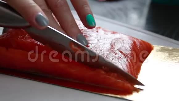 女人用刀子在厨房的塑料板上切一块金属一块新鲜的鲑鱼视频的预览图