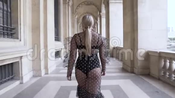 性感的金发女人穿着黑色的裙子走在古代宫殿附近行动有吸引力的铅丝尺寸模型的后视图视频的预览图