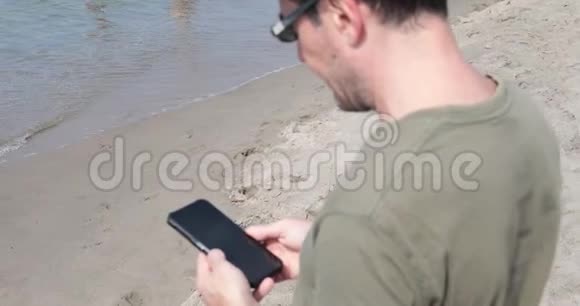 在海滩上查看留言的人视频的预览图