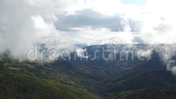 空中飞行在高山上的森林上空穿过云层视频的预览图