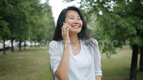 欢乐的亚洲女学生在夏天的绿色公园里用手机聊天视频的预览图
