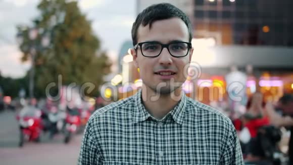 戴眼镜的快乐男人微笑着站在现代城市的步行街视频的预览图