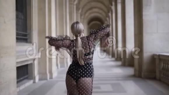 一个非常漂亮的年轻金发模特穿着黑色透明的裙子沿着柱子走着视频的预览图