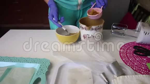 一个女人把果酱放在量勺里然后把它放在容器里桌子的旁边是制作工具视频的预览图