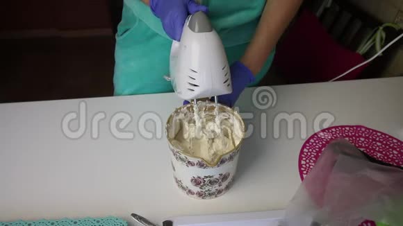 一个女人用搅拌机在容器里准备棉花糖这时男人从炖锅里加入了容器糖浆视频的预览图