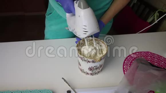 一个女人用搅拌机在容器里准备棉花糖用勺子把它从殴打者身上移开视频的预览图