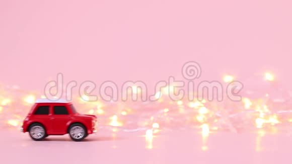 交付概念红色儿童玩具车和粉红色背景上的金色闪烁花环视频的预览图