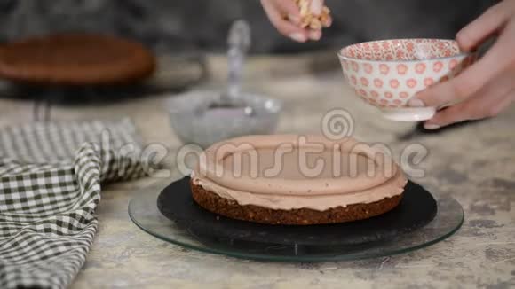 糕点厨师在巧克力海绵蛋糕上撒上榛子用坚果做蛋糕视频的预览图