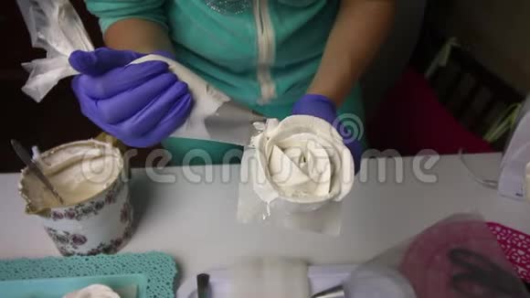 一个女人使用糕点袋和喷嘴形成玫瑰花瓣从棉花糖把完成的棉花糖从看台上移走视频的预览图