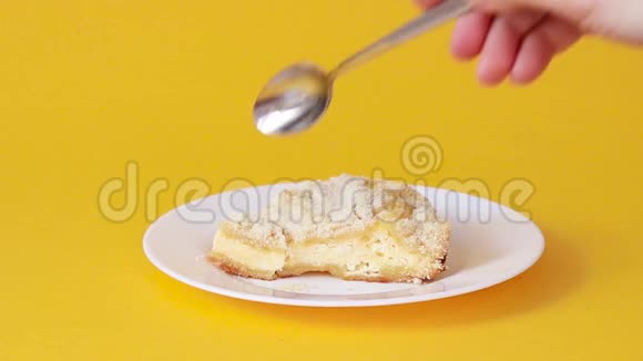 一块蛋糕上面有白陶瓷盘上的干酪背景是黄色的女人手拿一块蛋糕视频的预览图