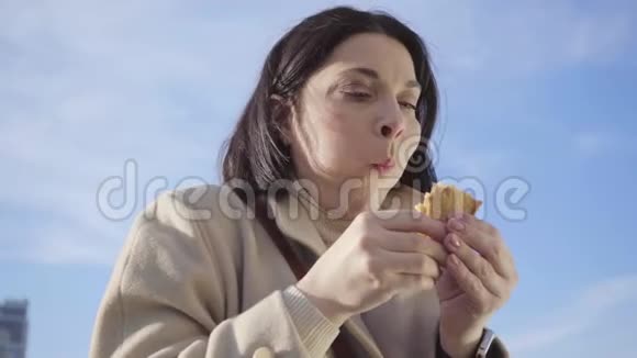 丰满的白种人女人吃三明治的特写镜头自信疲惫的商务小姐在城里休息视频的预览图