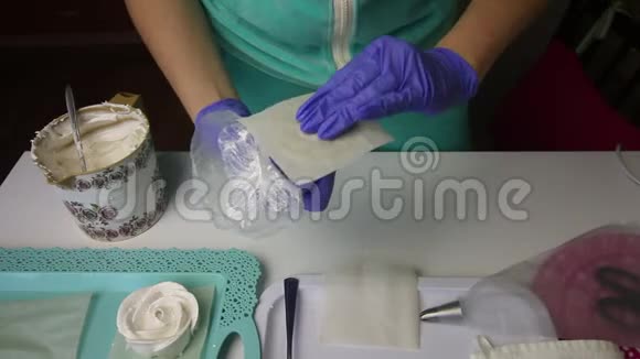 一个女人把纸放在看台上用糕点袋和喷嘴从棉花糖上形成玫瑰花瓣煮棉花糖视频的预览图