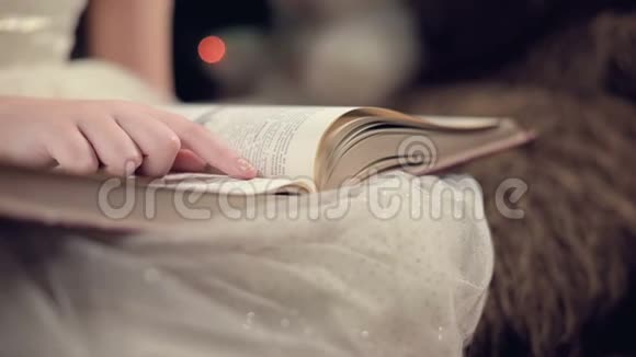 一个身穿节日礼服手里拿着一本书的金发小女孩坐在背景软玩具旁边视频的预览图