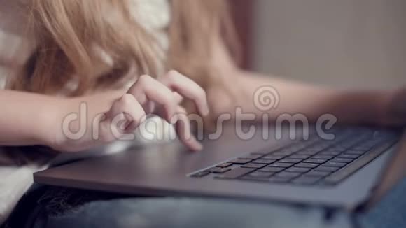 在笔记本电脑键盘上一个小女孩的手特写了一个浅浅的景深利用年轻一代的概念视频的预览图