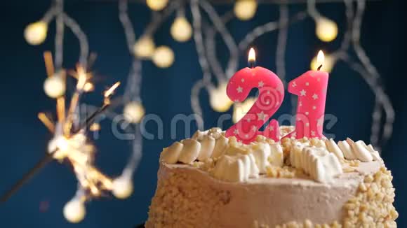 生日蛋糕与21号燃烧粉红色蜡烛和闪闪发光的蓝色背景慢速运动和特写镜头视频的预览图